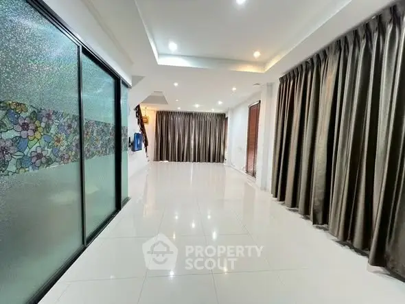Spacious living room with elegant curtains and glossy tiled flooring, perfect for modern living.