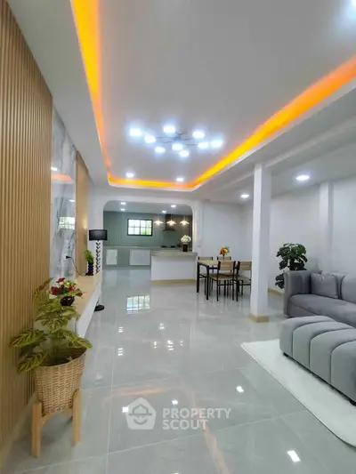 Spacious modern living room with stylish lighting and open kitchen layout, perfect for entertaining.