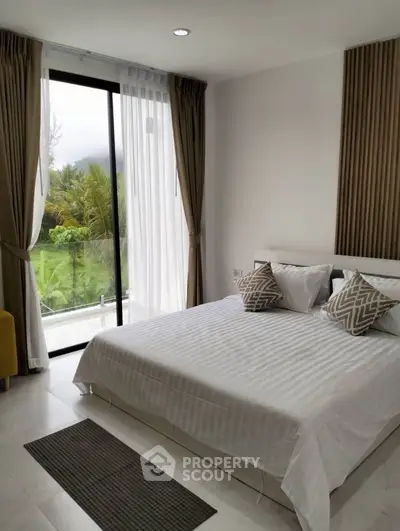 Spacious bedroom with large window offering lush garden view, modern decor, and cozy ambiance.