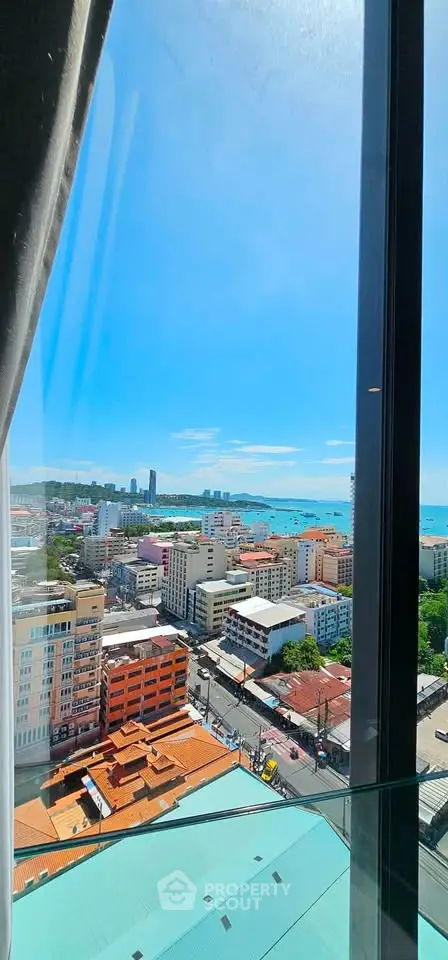 Stunning high-rise view of cityscape and ocean from a modern apartment window.