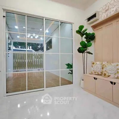 Modern interior with sliding glass doors and elegant decor, featuring a cozy seating area and lush greenery.