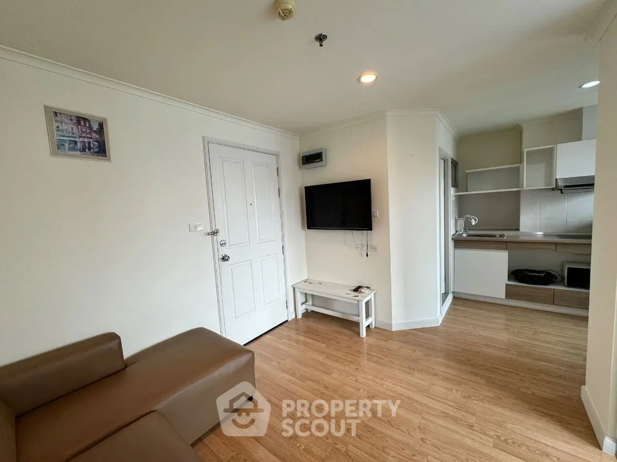 Modern living room with open kitchen, featuring sleek furniture and wooden flooring.