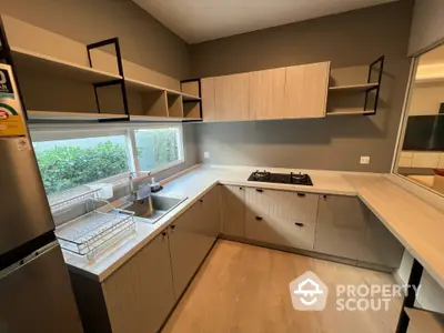 Modern kitchen with sleek cabinetry and gas stove, featuring ample natural light and stylish open shelving.