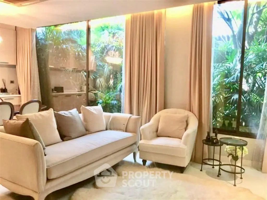Luxurious living room with elegant sofa, armchair, and lush garden view.