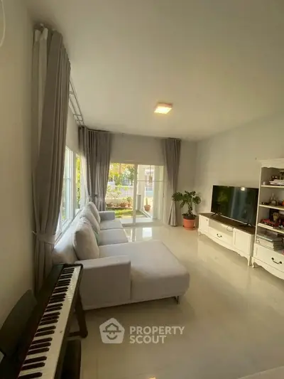 Spacious living room with modern decor, large windows, and a cozy sectional sofa.