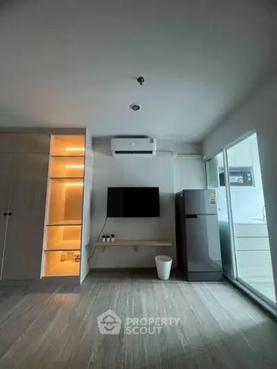 Modern living room with sleek design, featuring built-in storage, air conditioning, and a compact kitchen area.