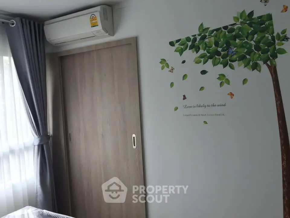 Charming bedroom with nature-themed wall art and sliding closet door, featuring natural light and air conditioning.
