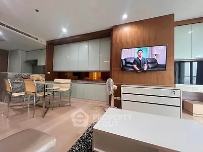 Modern living room with sleek design and integrated kitchen area, featuring a wall-mounted TV and stylish dining set.