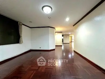 Spacious living room with polished wooden floors and elegant lighting in a modern apartment.