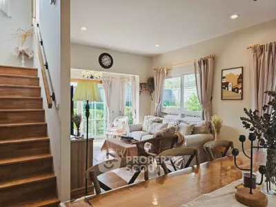 Charming living room with cozy decor and natural light, featuring a staircase and garden view.