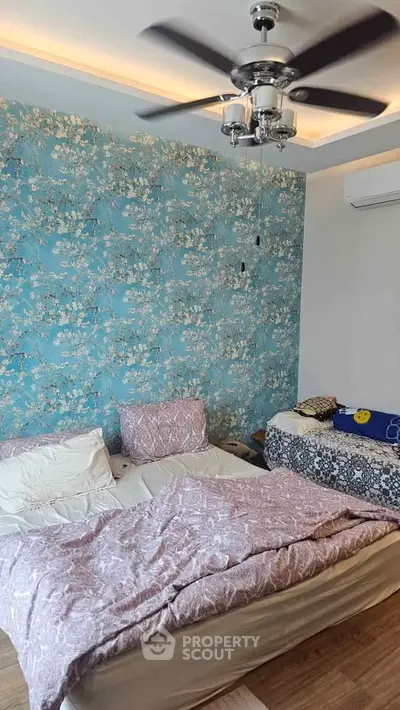 Charming bedroom with floral accent wall and modern ceiling fan, perfect for cozy living.