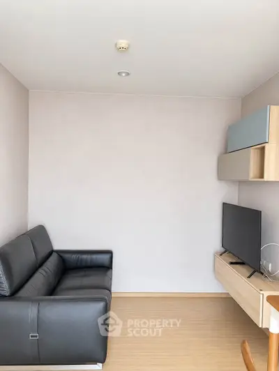 Modern minimalist living room with sleek black sofa and wall-mounted TV
