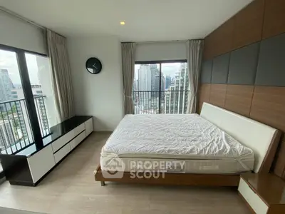 Spacious bedroom with city view and modern furnishings in high-rise apartment.