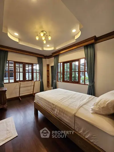 Spacious bedroom with elegant wooden flooring and large windows for natural light.