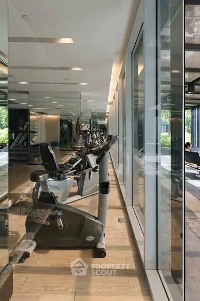 Modern gym with exercise bikes and glass walls in luxury building