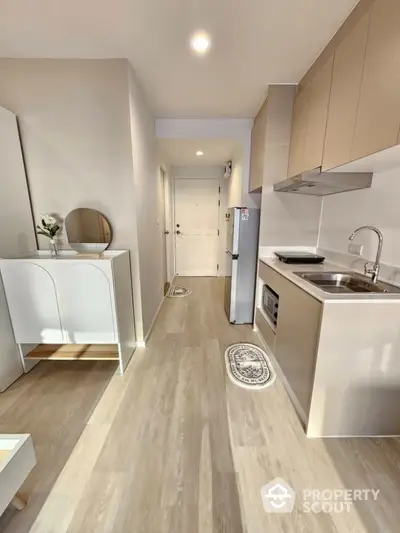 Modern compact kitchen with sleek cabinetry and integrated appliances in a bright apartment.