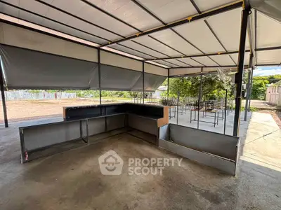 Spacious outdoor covered area with metal framework and open surroundings, ideal for versatile use.