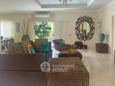 Spacious living room with elegant decor and large mirror, featuring comfortable seating and stylish accents.