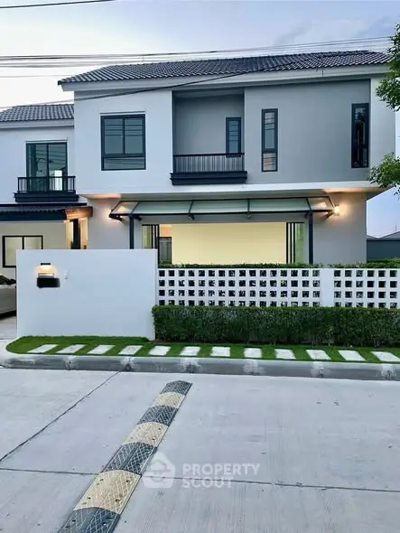 Modern two-story house with sleek design and landscaped front yard in a serene neighborhood.