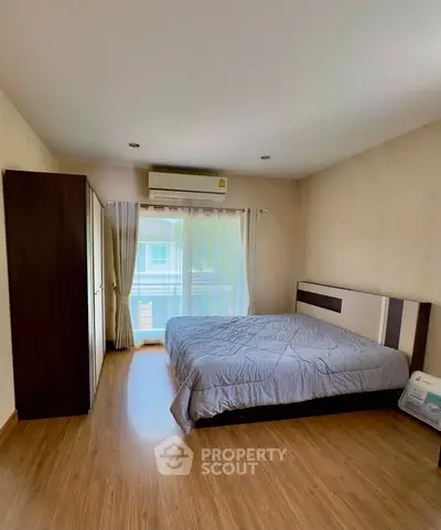Spacious bedroom with large window and modern furnishings in a cozy apartment.