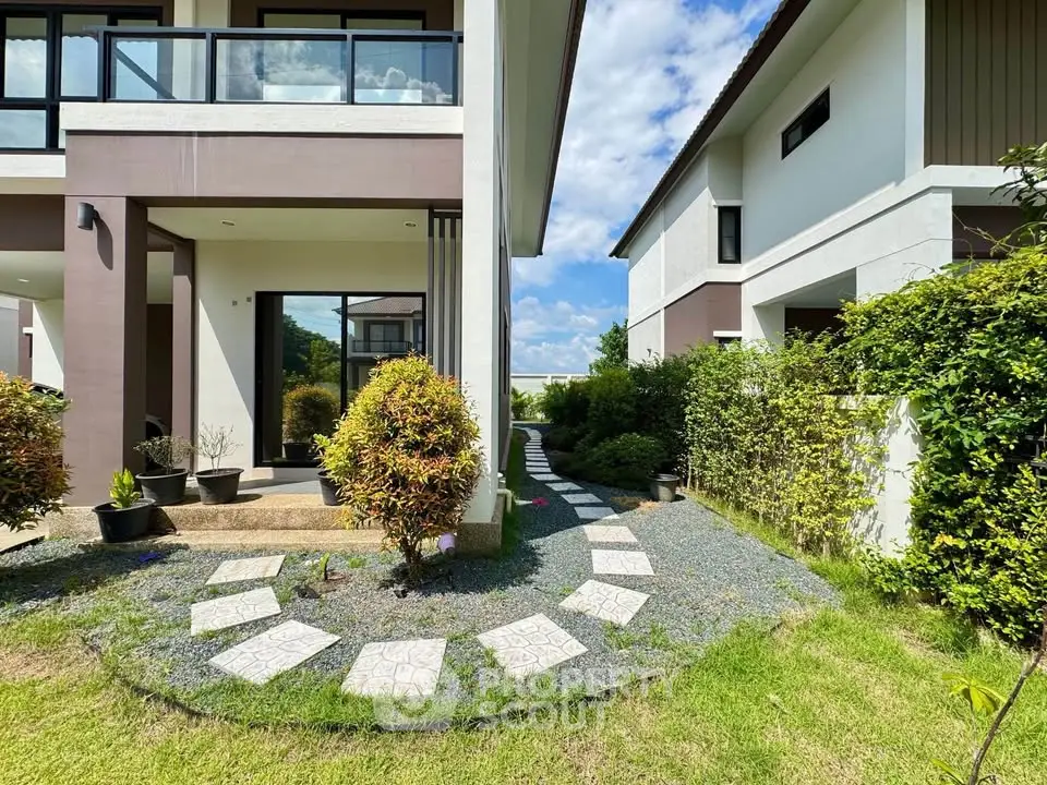 Modern two-story house with landscaped garden and pathway, showcasing contemporary architecture and lush greenery.