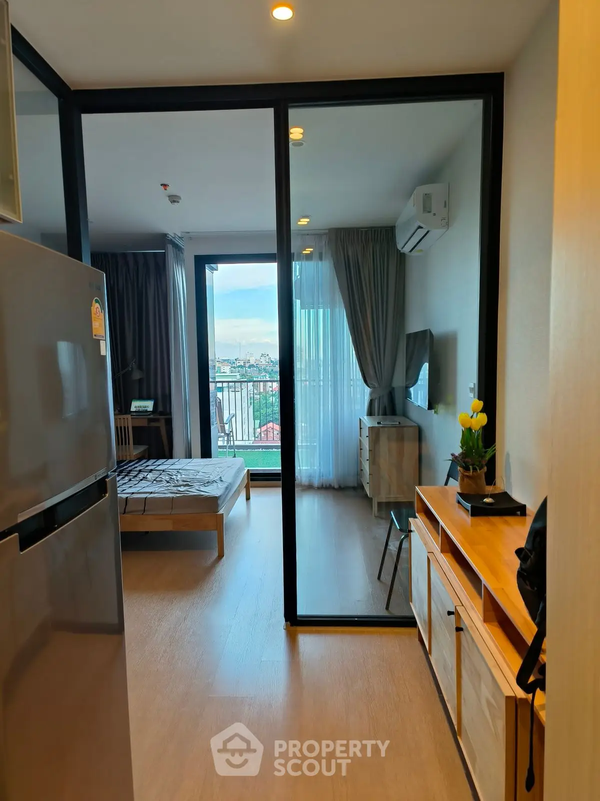 Modern studio apartment with balcony and city view, featuring sleek interior design and natural light.