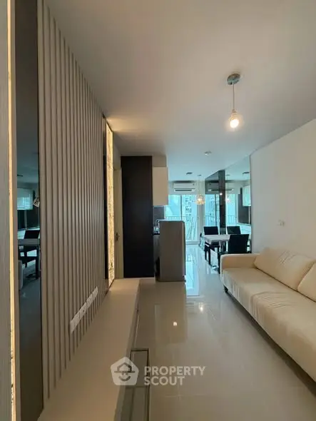 Modern living room with sleek design and neutral tones, featuring a comfortable sofa and dining area.