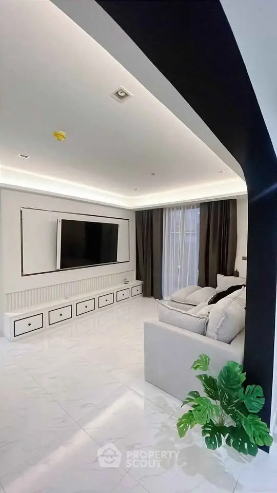 Luxurious modern living room with sleek design, large TV, and elegant decor.