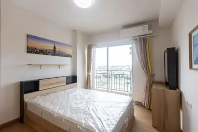 Bright bedroom with large window and balcony access, featuring modern decor and air conditioning.