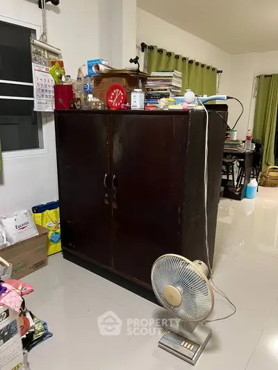 Cozy living space with wooden cabinet and fan, ideal for organizing and relaxing.
