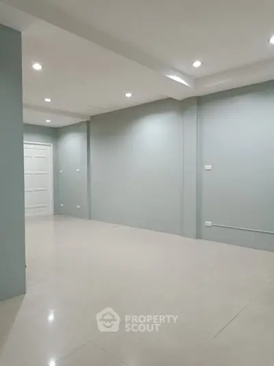 Spacious empty room with modern lighting and sleek tile flooring, perfect for customization.