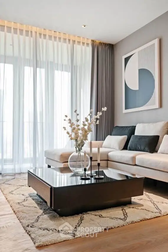 Elegant living room with modern decor, featuring a cozy sofa, stylish coffee table, and large windows with sheer curtains.