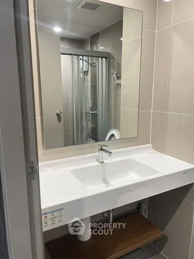 Modern bathroom with sleek sink and large mirror in contemporary apartment.