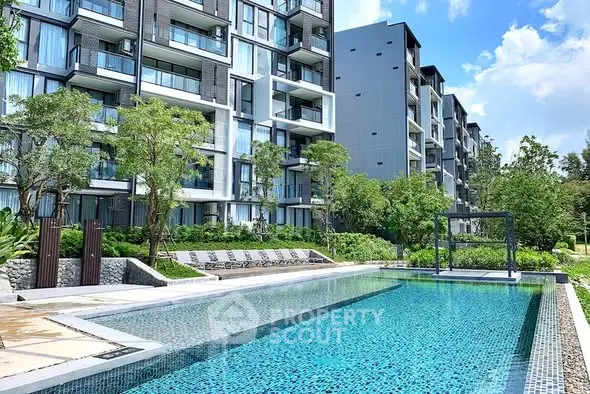 Modern apartment complex with a luxurious outdoor pool and lush greenery.