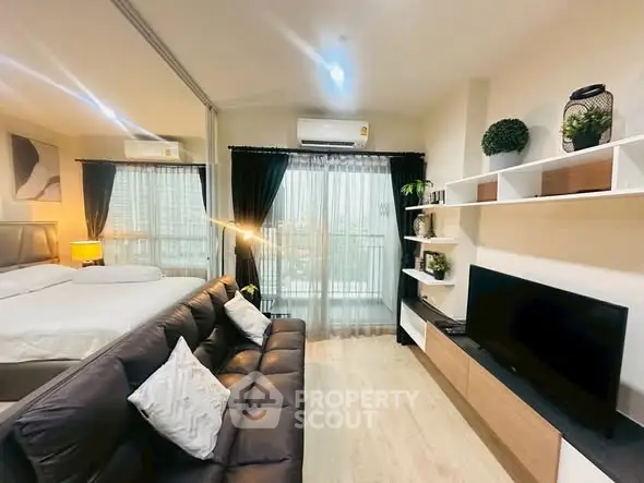 Modern living room with sleek design, cozy sofa, and large TV, adjacent to a stylish bedroom.