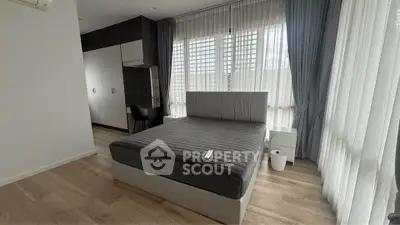 Spacious bedroom with modern decor and large windows for natural light.