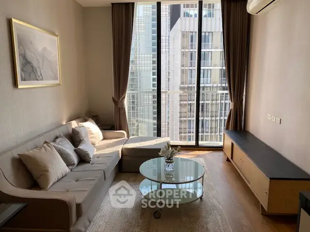 Modern living room with large windows and city view, featuring elegant furniture and decor.