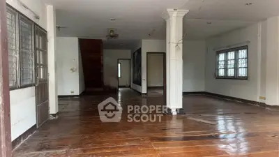 Spacious empty living room with wooden floors and large windows in a residential property.