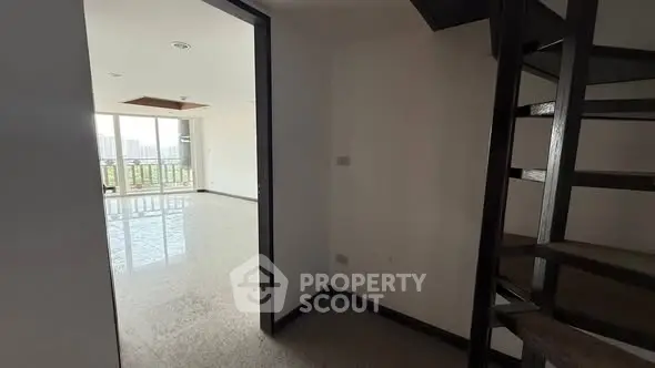 Spacious apartment with spiral staircase and large windows offering city views.