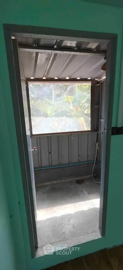 Simple outdoor shower area with metal roofing and garden view