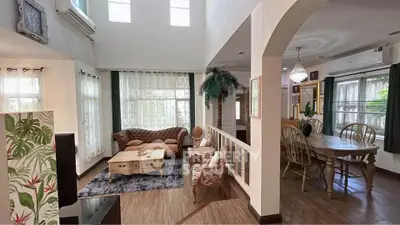 Spacious living room with elegant decor and dining area, featuring high ceilings and abundant natural light.
