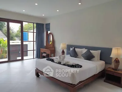 Spacious bedroom with elegant decor and large windows offering natural light.