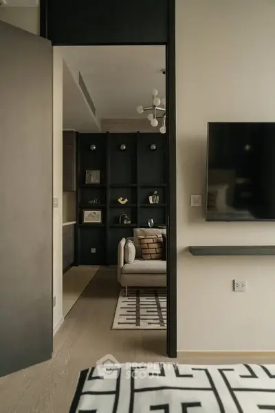 Modern living room with stylish decor and wall-mounted TV, featuring a cozy seating area and elegant shelving.