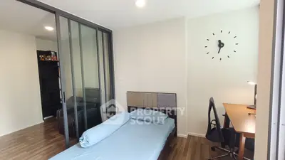 Modern bedroom with sleek design and glass partition, featuring a cozy bed and stylish workspace.