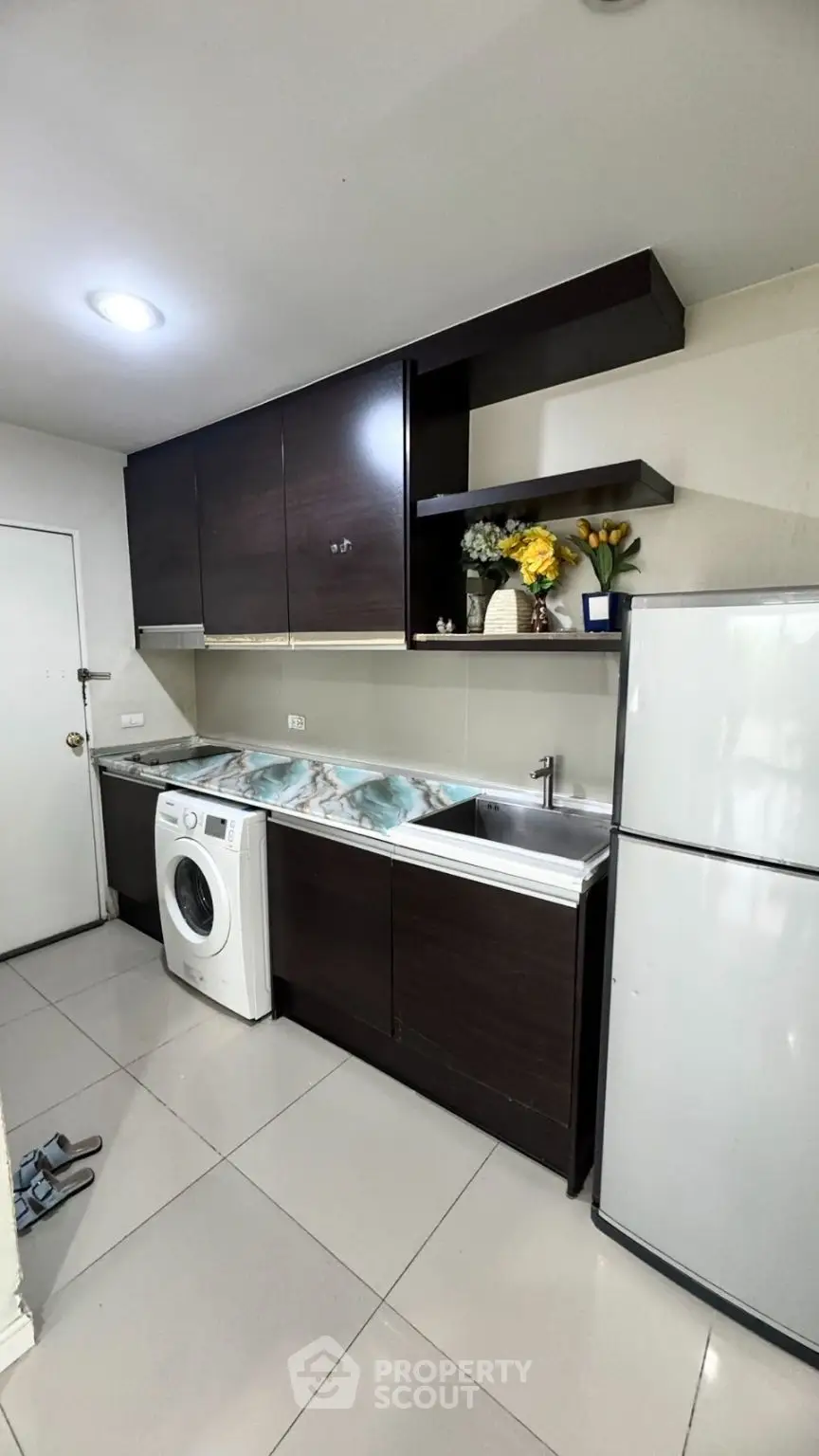 Modern kitchen with sleek cabinets, washing machine, and fridge in a compact layout.