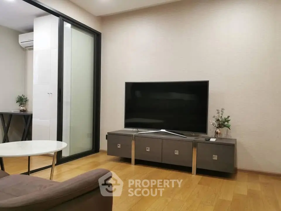 Modern living room with sleek TV stand and wooden flooring, featuring a stylish glass partition.