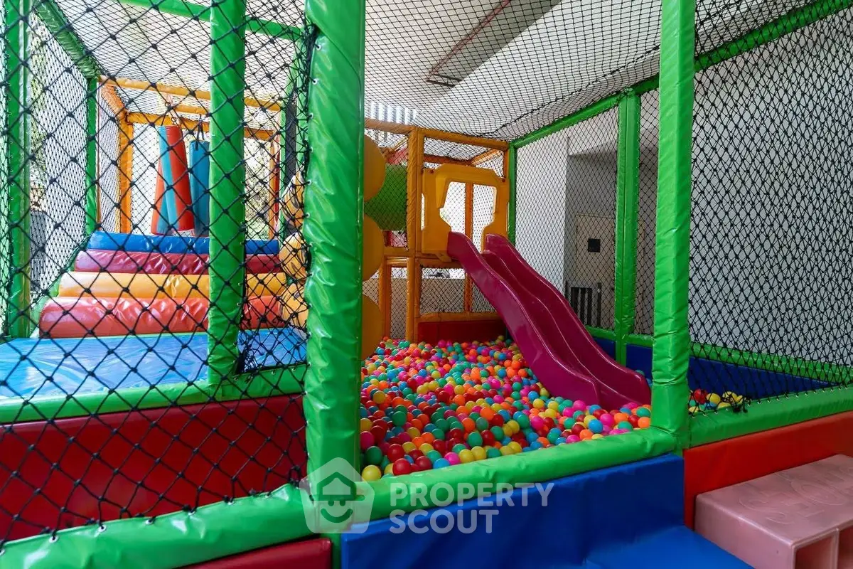 Vibrant indoor playground with slides and ball pit in modern residential building.