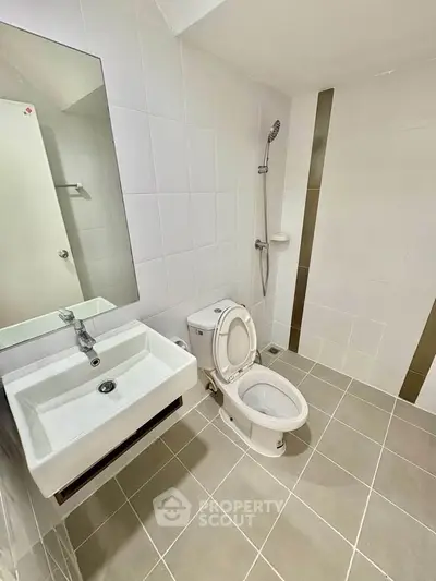 Modern bathroom with sleek fixtures and minimalist design, featuring a shower, toilet, and sink.
