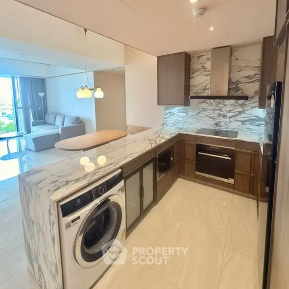 Luxurious modern kitchen with marble countertops and built-in appliances in open layout design.