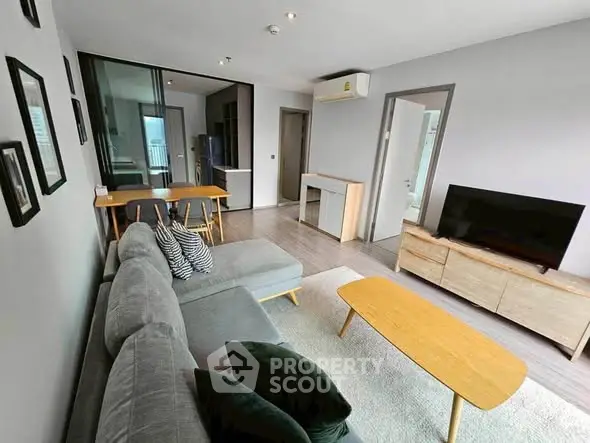 Modern living room with sleek furniture and open layout, featuring a cozy sofa and flat-screen TV.